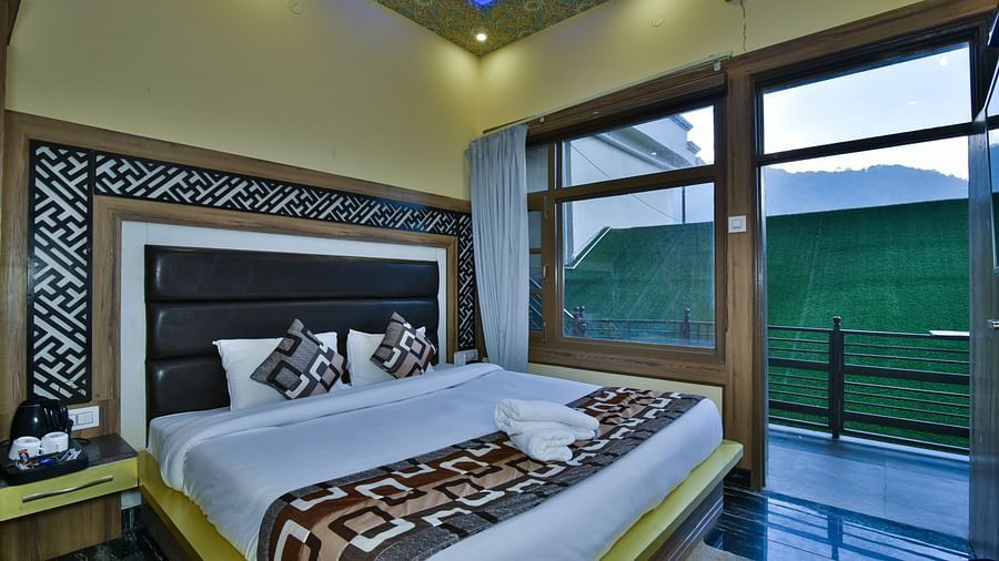 A Deluxe Room at DLS Dalhousie Valley Resort with a  king size bed and a balcony 
